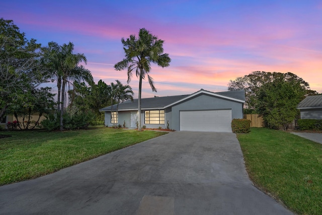 single story home featuring a garage and a lawn