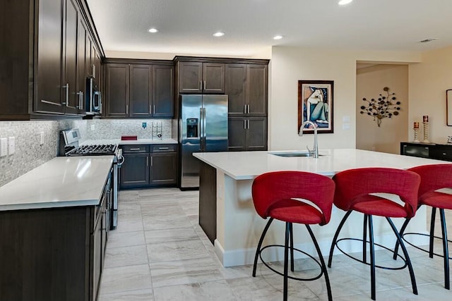 kitchen with sink, a kitchen breakfast bar, stainless steel appliances, and a kitchen island with sink