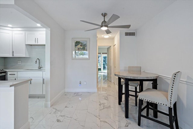 dining area with ceiling fan and sink