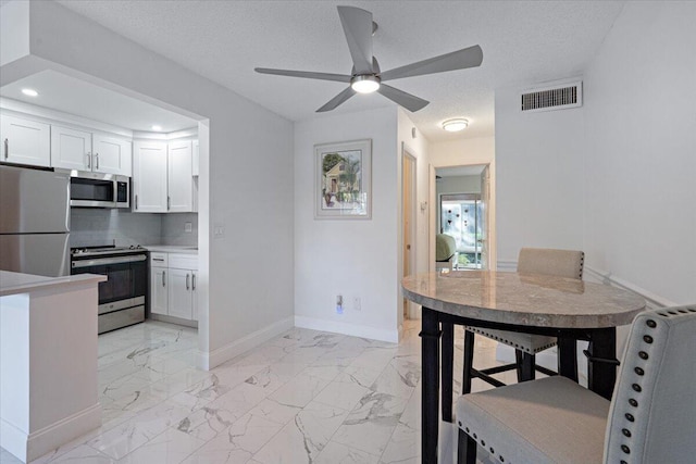 kitchen with tasteful backsplash, ceiling fan, white cabinetry, appliances with stainless steel finishes, and a textured ceiling