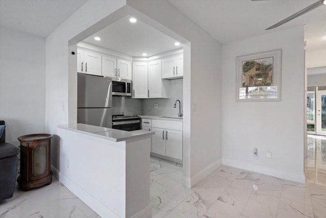 kitchen with white cabinetry, stainless steel appliances, tasteful backsplash, sink, and kitchen peninsula