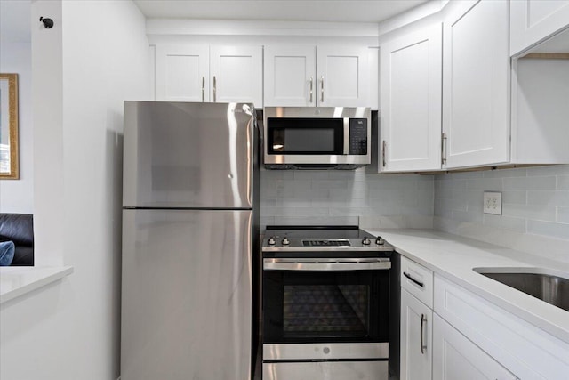 kitchen featuring decorative backsplash, light stone countertops, white cabinetry, and appliances with stainless steel finishes