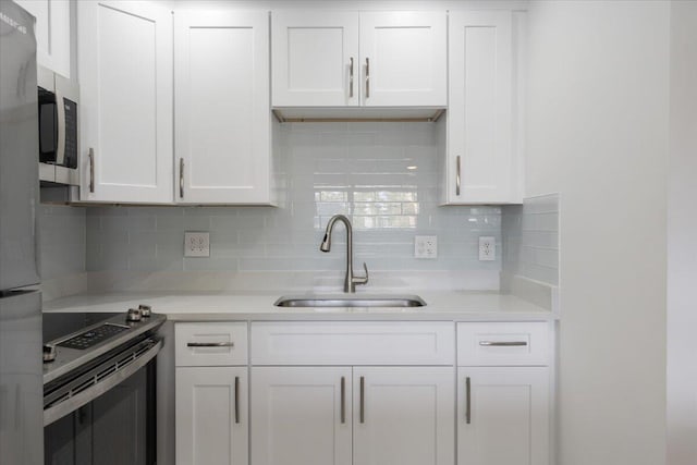 kitchen with decorative backsplash, sink, white cabinetry, and stainless steel range with electric stovetop