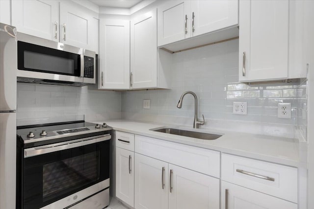 kitchen with tasteful backsplash, white cabinets, sink, and stainless steel appliances