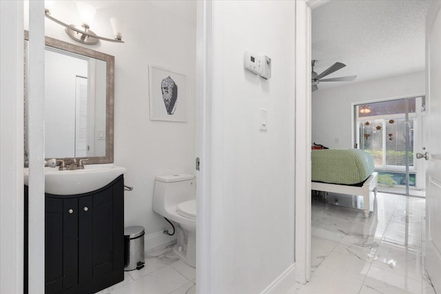 bathroom featuring ceiling fan, vanity, toilet, and a textured ceiling