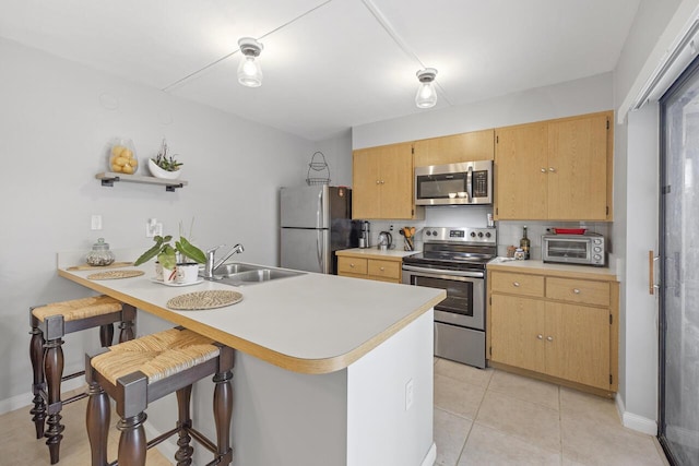 kitchen with a kitchen bar, sink, appliances with stainless steel finishes, and kitchen peninsula