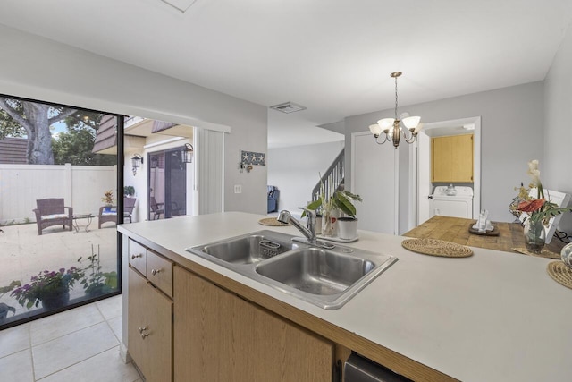 kitchen with washer and dryer, decorative light fixtures, sink, a notable chandelier, and light tile patterned flooring