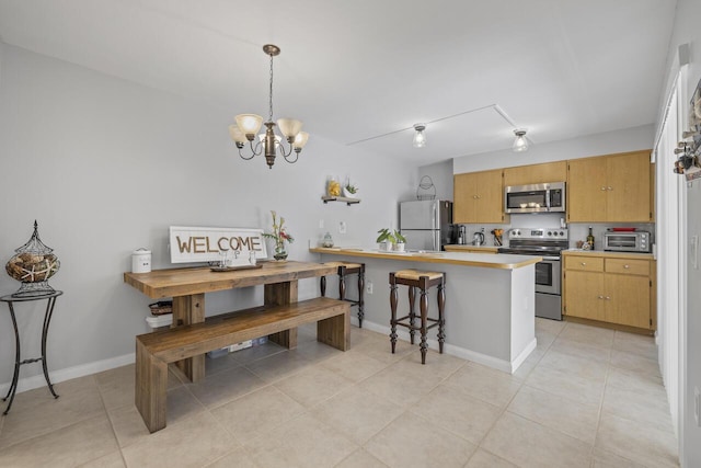 kitchen with pendant lighting, kitchen peninsula, an inviting chandelier, stainless steel appliances, and light tile patterned floors