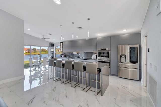 kitchen with hanging light fixtures, gray cabinets, a water view, and appliances with stainless steel finishes