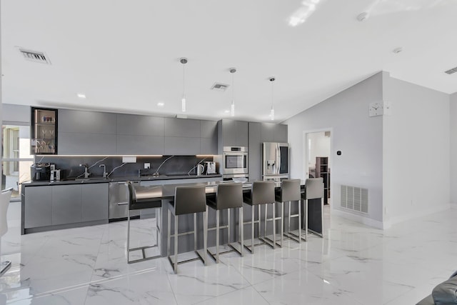 kitchen featuring a spacious island, a kitchen bar, hanging light fixtures, appliances with stainless steel finishes, and gray cabinets