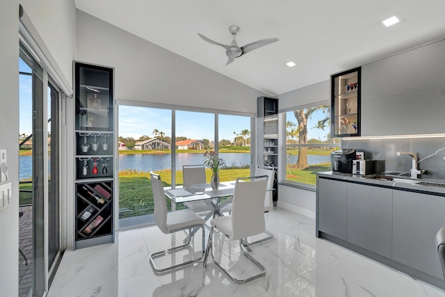 dining space featuring a water view, sink, lofted ceiling, and ceiling fan