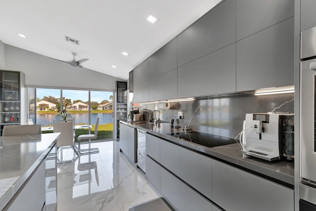 kitchen featuring lofted ceiling, a water view, black electric cooktop, gray cabinets, and decorative backsplash