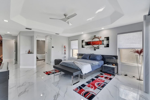 bedroom with connected bathroom, ceiling fan, and a tray ceiling