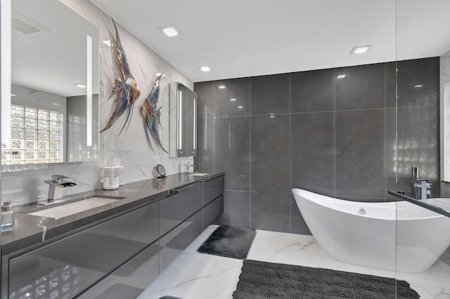 bathroom featuring tile walls, a tub to relax in, and vanity