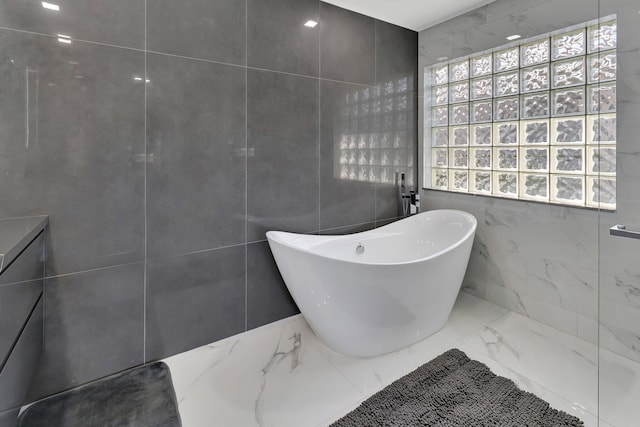 bathroom with a bathing tub and tile walls