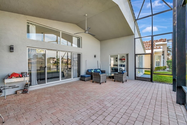 view of patio featuring outdoor lounge area, ceiling fan, and glass enclosure