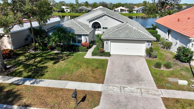 view of front of property with a garage, a front yard, and a water view