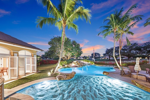 pool at dusk with a patio area