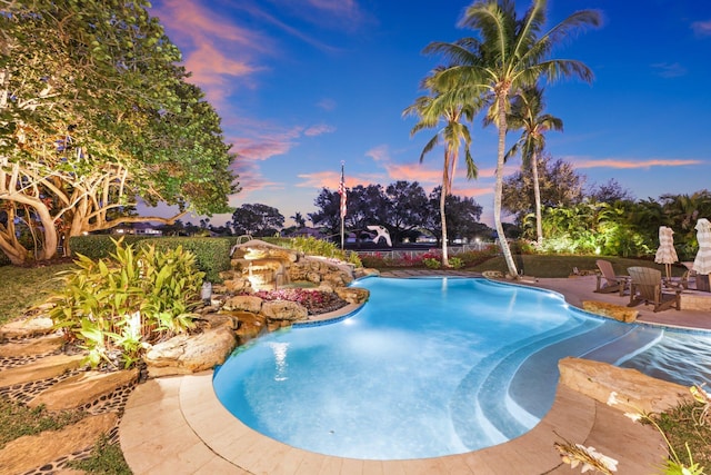 pool at dusk featuring a patio