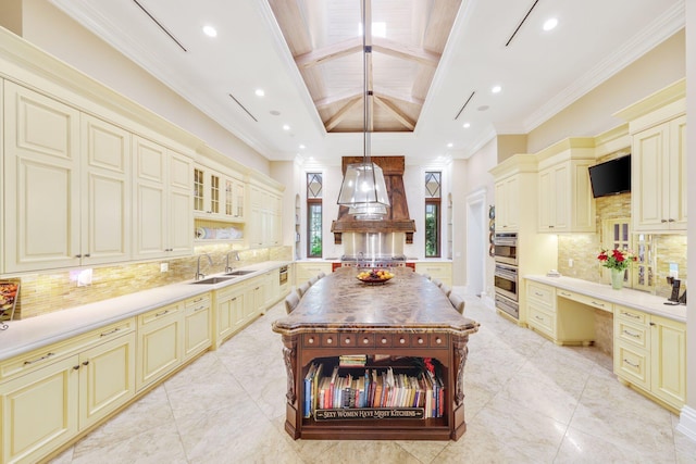 kitchen featuring tasteful backsplash, hanging light fixtures, built in desk, and cream cabinetry