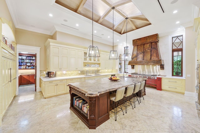 kitchen with pendant lighting, a kitchen breakfast bar, custom exhaust hood, a large island, and cream cabinets