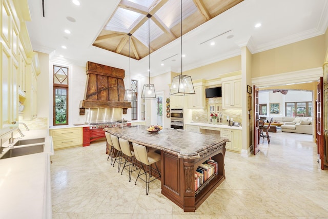 kitchen with pendant lighting, tasteful backsplash, sink, a breakfast bar area, and a center island