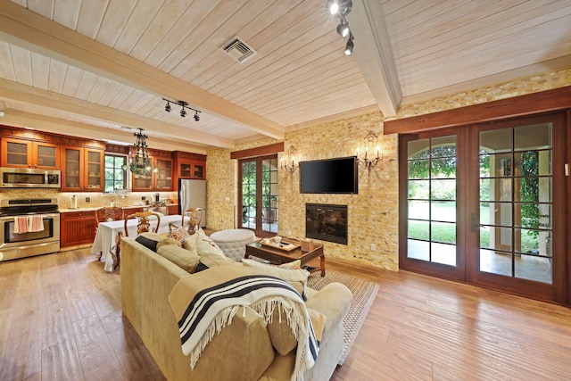 living room featuring light hardwood / wood-style flooring, a fireplace, wooden ceiling, french doors, and beamed ceiling