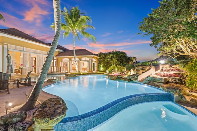 pool at dusk with a patio area