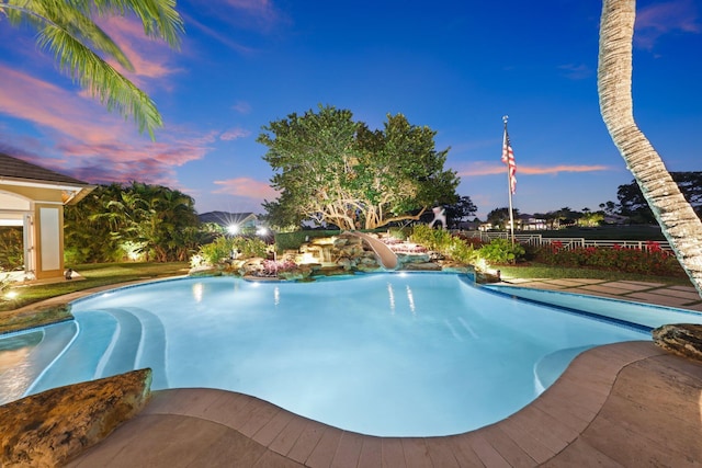 pool at dusk featuring a water slide