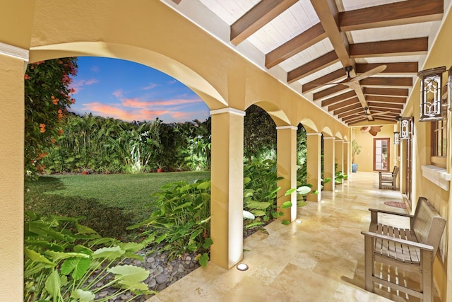 patio terrace at dusk with ceiling fan and a lawn