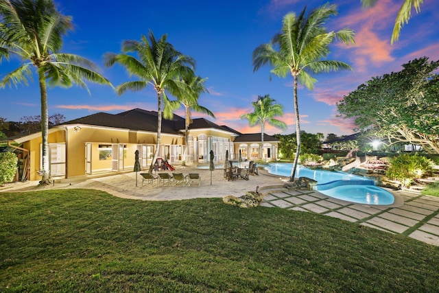 pool at dusk with a yard and a patio