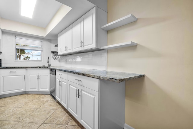 kitchen with sink, decorative backsplash, dark stone countertops, and white cabinetry