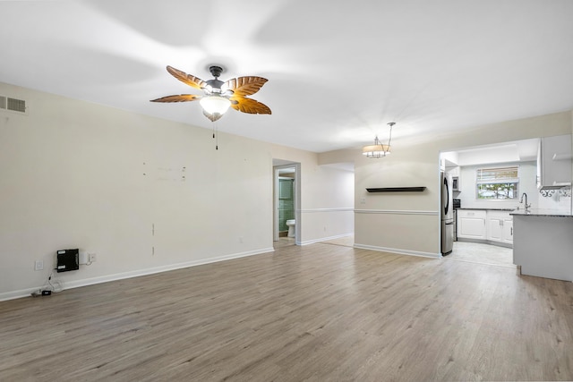 unfurnished living room with ceiling fan, light hardwood / wood-style flooring, and sink