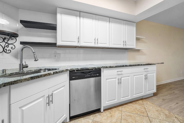 kitchen with dishwasher, white cabinetry, dark stone countertops, sink, and light tile patterned flooring