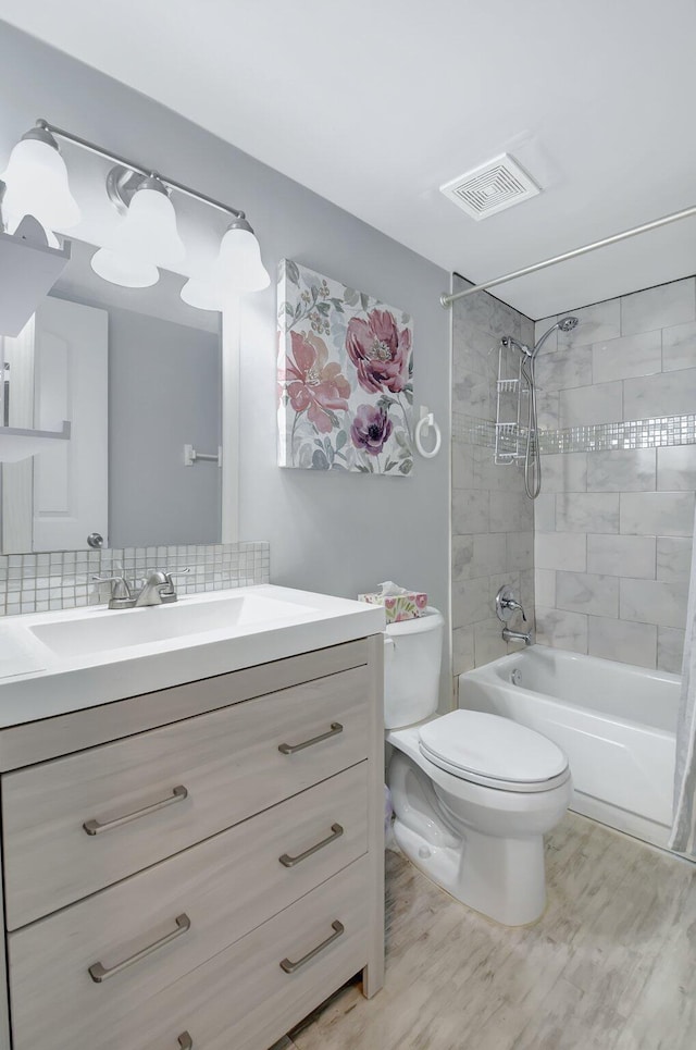 full bathroom with toilet, tiled shower / bath, vanity, and hardwood / wood-style floors