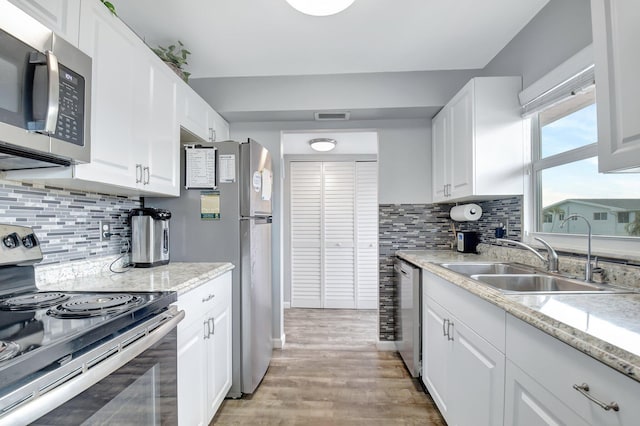 kitchen featuring sink, white cabinets, light hardwood / wood-style flooring, and stainless steel appliances