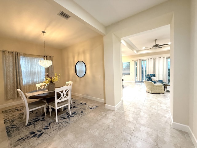 dining area featuring ceiling fan with notable chandelier and a raised ceiling