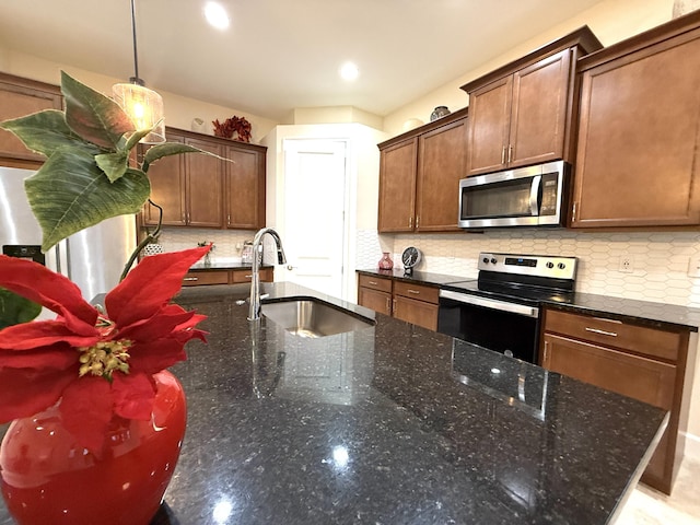 kitchen with decorative light fixtures, appliances with stainless steel finishes, sink, and dark stone countertops