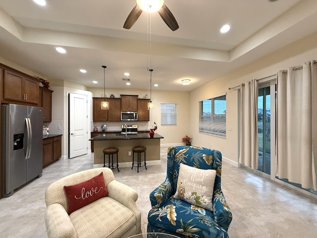 kitchen featuring ceiling fan, appliances with stainless steel finishes, tasteful backsplash, decorative light fixtures, and a kitchen island with sink