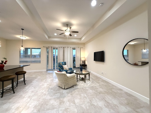 living room with ceiling fan and a raised ceiling