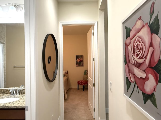 corridor with sink and light colored carpet