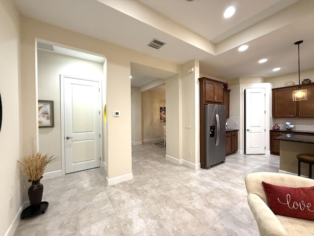 kitchen featuring decorative light fixtures, decorative backsplash, stainless steel fridge, and dark brown cabinets