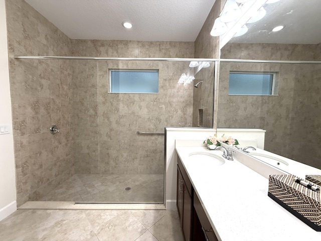 bathroom with vanity, tile patterned flooring, a textured ceiling, and a tile shower