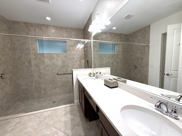 bathroom featuring vanity, tile patterned flooring, and tiled shower