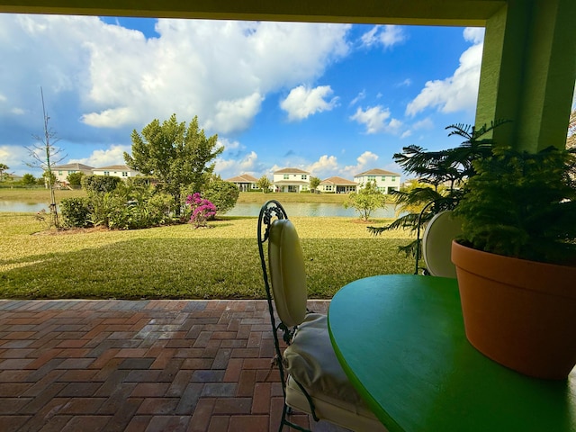 exterior space with a water view, a patio area, and a lawn