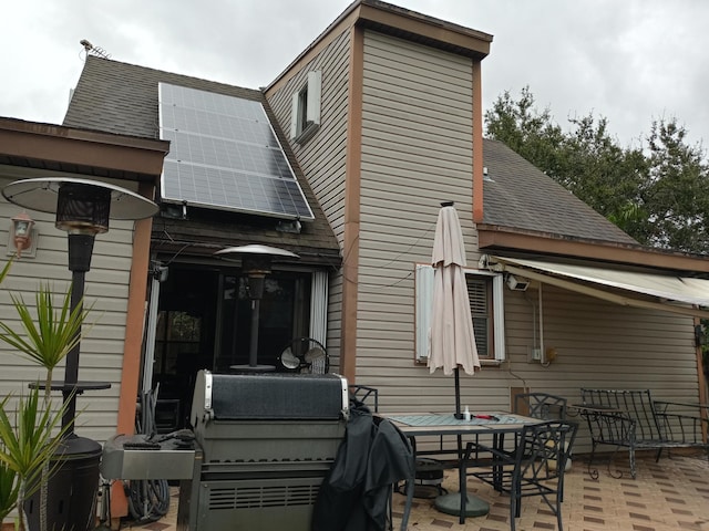 5266 Greenwood Dr, Delray Beach, FL 33484 - back of property with a patio, outdoor dining area, solar panels, and a shingled roof
