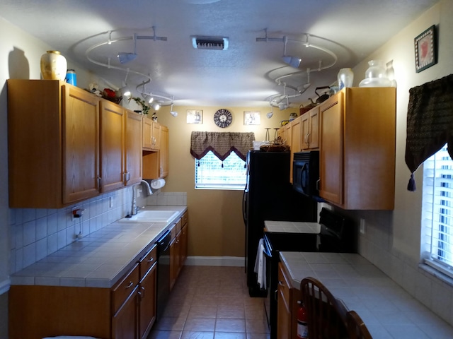 kitchen featuring decorative backsplash, sink, black appliances, and tile countertops