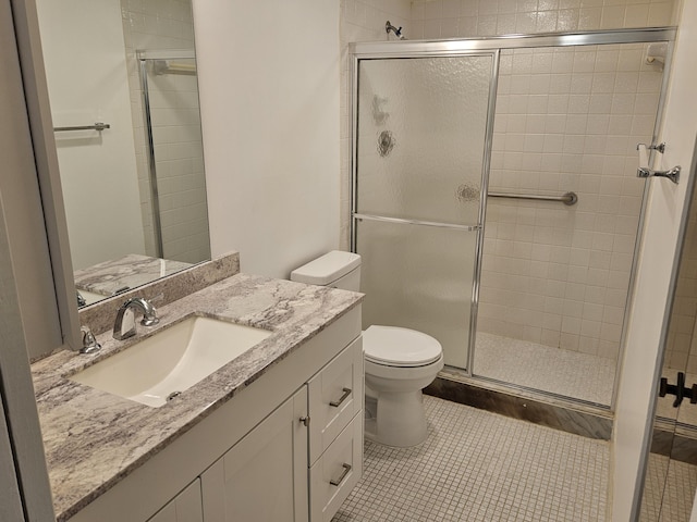 bathroom with toilet, vanity, a shower with door, and tile patterned floors