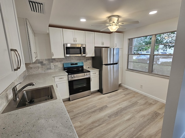 kitchen with decorative backsplash, sink, light stone countertops, appliances with stainless steel finishes, and white cabinets