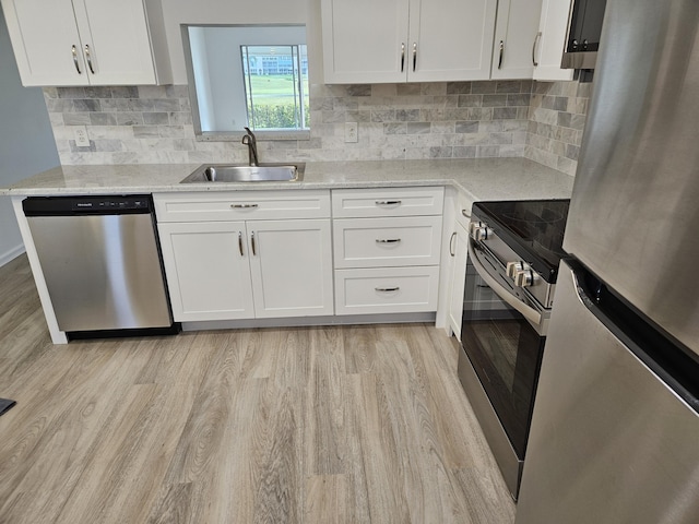 kitchen with white cabinets, sink, light stone counters, and stainless steel appliances